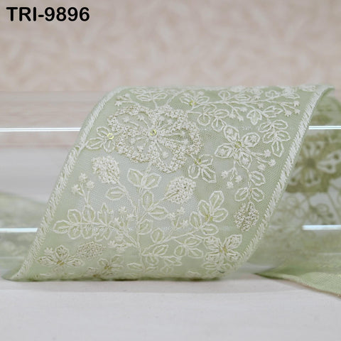 a close-up view of a decorative fabric with a floral pattern, featuring a pale green color.