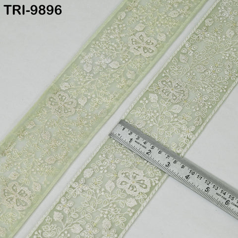 a close-up view of a decorative fabric with a floral pattern, featuring a ruler placed on top of it to measure its length.