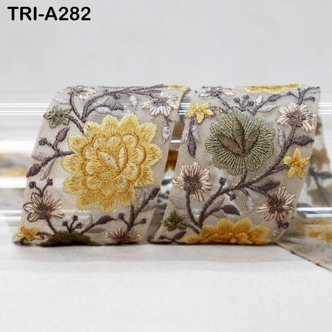 two pieces of fabric with intricate floral embroidery, including yellow and green flowers, as well as leaves and stems.