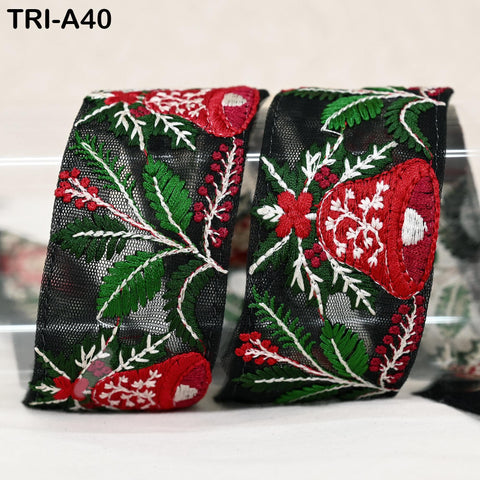 two decorative fabric pieces with a floral pattern in red, green, and white colors. The fabric appears to be a ribbon or a piece of clothing, with the intricate embroidery and floral designs visible.
