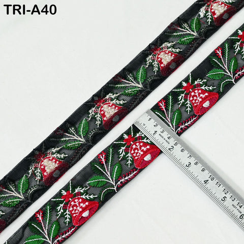 a decorative ribbon with a floral pattern, including red and green flowers, leaves, and other natural elements. The ribbon is placed next to a ruler, which is used to measure the length of the ribbon.