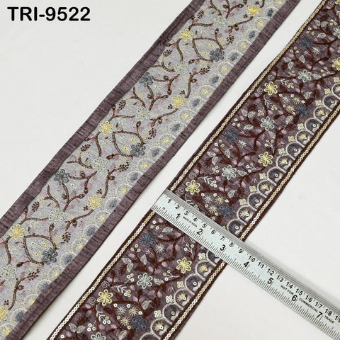 two pieces of fabric with intricate floral patterns, one in a darker shade of purple and the other in a lighter shade of purple. A ruler is placed on the right side of the fabric, indicating the size or dimensions of the fabric.