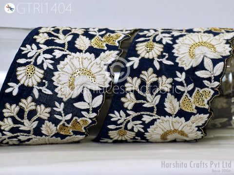 a close-up view of a decorative fabric with a floral pattern in shades of blue and white. The fabric appears to be made of silk or a similar material, and the intricate embroidery and embellishments create a visually appealing and detailed design.