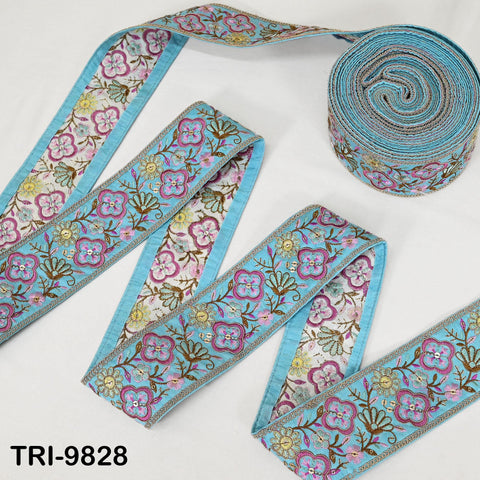 a collection of decorative fabric pieces, including a blue and white floral patterned ribbon and a roll of the same ribbon.