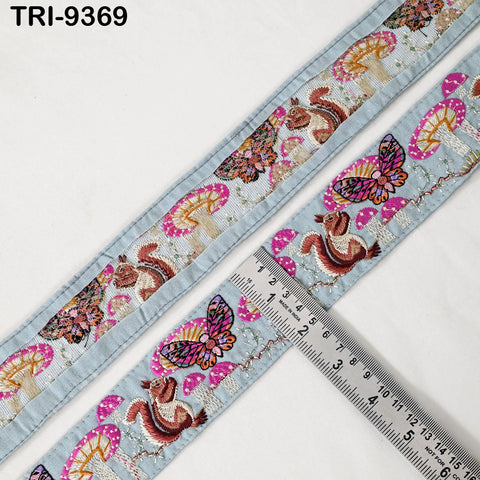 a decorative fabric with a repeating pattern of butterflies and mushrooms. The fabric is placed next to a ruler, which is used to measure the length of the fabric.