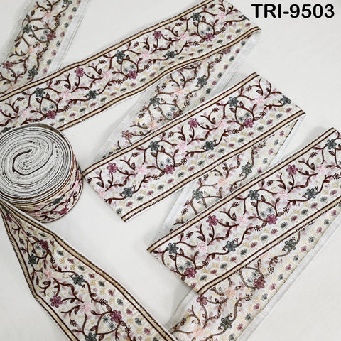 a collection of decorative fabric pieces with intricate floral patterns. The fabric appears to be a type of lace or textile with a repeating floral motif. The pieces are arranged on a white background, and there is a roll of the same fabric visible in the foreground.
