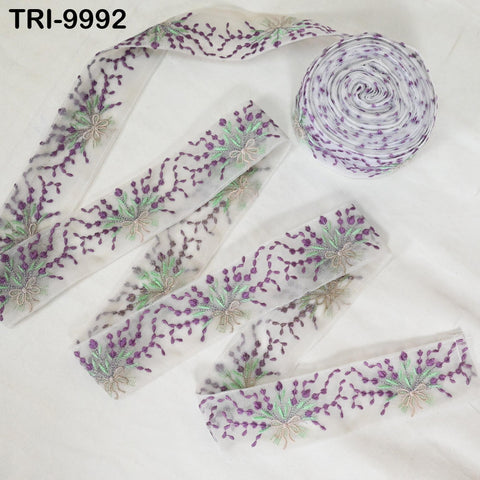 a collection of fabric pieces with a floral pattern, including a spool of thread and a ribbon.