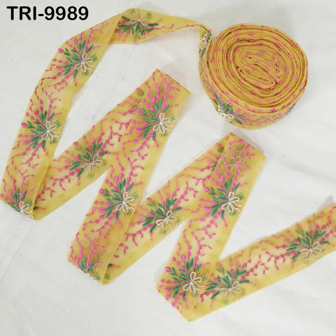 a yellow fabric with a floral pattern, including pink and green flowers, and a spool of the same fabric.