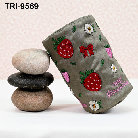 a gray fabric with a strawberry pattern, a stack of rocks, and a white flower on a table.
