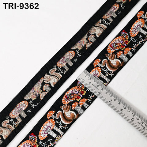a decorative black and white fabric with a repeating pattern of mushrooms and stars. A ruler is placed on the fabric, indicating its size.