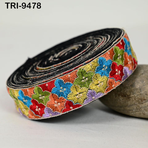 A colorful, embroidered fabric with a floral pattern is displayed on a white surface.