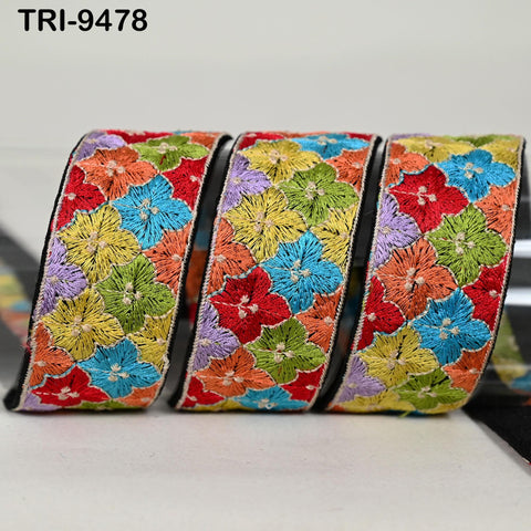 A colorful, embroidered ribbon with a repeating floral pattern in various shades of green, yellow, orange, and red.