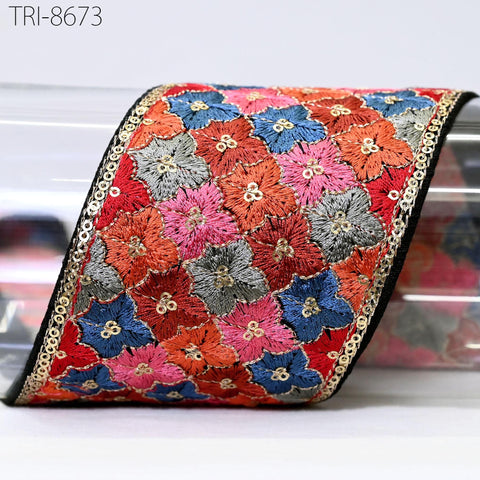 a decorative fabric with a floral pattern in various colors, including red, blue, and green. The fabric appears to be a decorative trim or border, with a black border around the edges. The image does not contain any text or other objects, and the focus is solely on the colorful floral design.