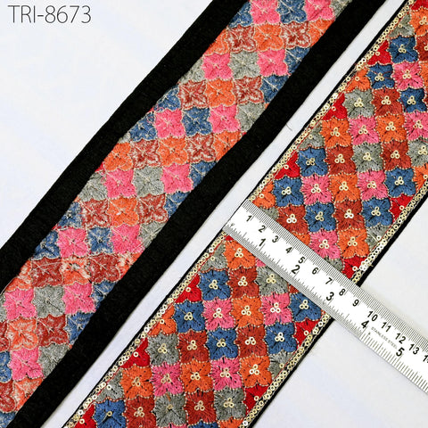 two pieces of fabric with a floral pattern, one with a black border and the other with a colorful border. A ruler is placed between the two pieces of fabric, indicating the size or length of the fabric.