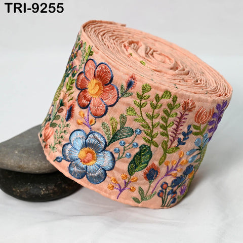 A rolled-up fabric with a floral pattern in shades of pink, blue, green, and orange, featuring various types of flowers and leaves.