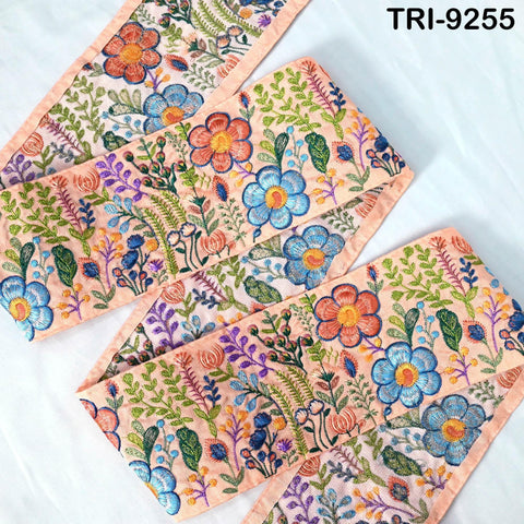 a close-up view of a decorative fabric with a floral pattern. The fabric features a variety of colorful flowers and leaves, creating a vibrant and intricate design. The fabric appears to be made of a soft, light-colored material, which adds to its overall aesthetic appeal.
