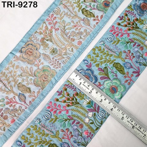 a close-up view of a decorative fabric with a floral pattern. The fabric is adorned with various colorful flowers and leaves, creating a visually appealing design. A ruler is placed on the fabric, likely for measuring purposes. The image does not contain any text or additional objects, and the focus is solely on the fabric and its intricate floral design.