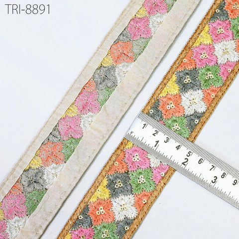 two pieces of fabric with a floral pattern, one with a beige border and the other with a gold border. A ruler is placed between the two pieces of fabric, indicating the size of the fabric.