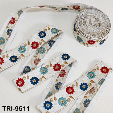 a collection of decorative fabric pieces, including a spool of white fabric with a floral pattern and several pieces of fabric with a similar floral pattern.