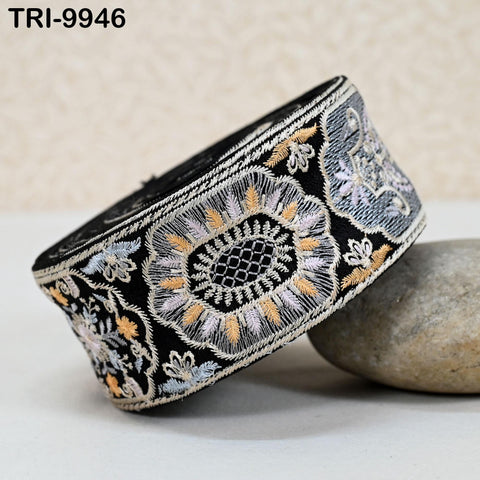 a decorative black and white fabric with intricate floral patterns and designs, including a large central flower design. The fabric appears to be a piece of clothing or accessory, possibly a headband or cuff.
