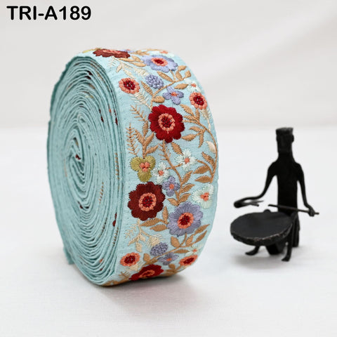 a large roll of embroidered fabric with a floral pattern, placed next to a small black figurine.