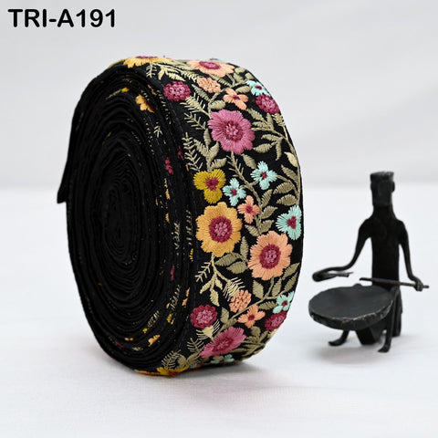 a large, colorful, floral-patterned fabric roll or ribbon, which appears to be a decorative item. Next to the fabric roll, there is a small black figurine or sculpture, possibly a drummer or a drummer's instrument. The background of the image is white, which helps to highlight the objects in the foreground.