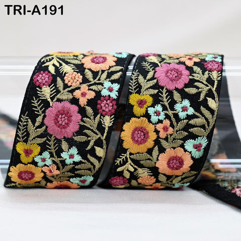 two pieces of fabric with a floral pattern, featuring a variety of colorful flowers and leaves. The fabric appears to be black with a vibrant, embroidered design.