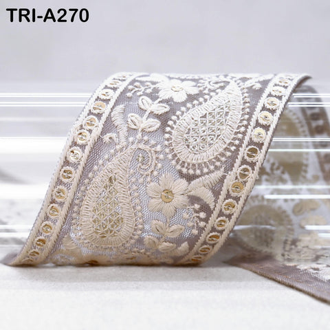 A close-up view of a decorative fabric with intricate floral patterns and paisley designs, featuring a light beige color.