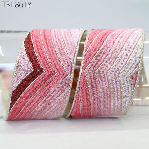 a decorative ribbon with a pink and red striped pattern, placed on a white surface.