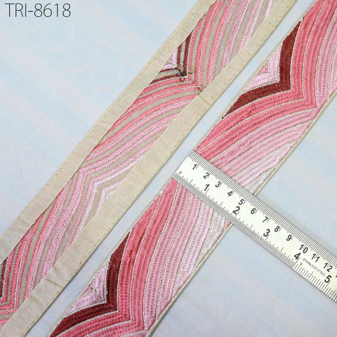 a close-up view of a decorative fabric with a pink and white striped pattern, placed next to a ruler for size comparison.