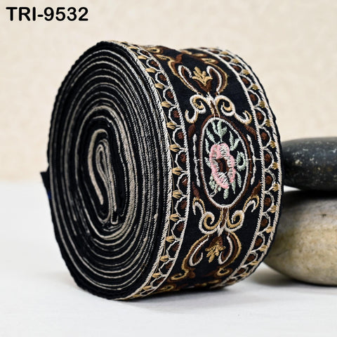 A close-up image of a black and gold embroidered fabric, featuring a floral design and a circular motif.