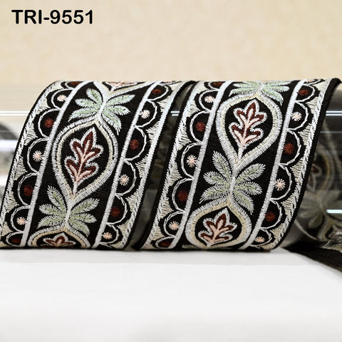 two decorative black and white fabric pieces with intricate floral and leaf patterns. The fabric appears to be made of a shiny material, possibly silk or satin, and is displayed on a white surface.