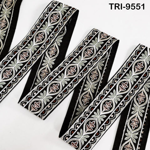 a close-up view of a decorative black and white fabric with a repeating pattern of floral and leaf designs. The fabric appears to be a type of lace or textile with a symmetrical, ornate design.