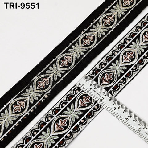 a decorative black and white fabric with a repeating pattern of floral and leaf designs. A ruler is placed next to the fabric, indicating the size or length of the fabric.