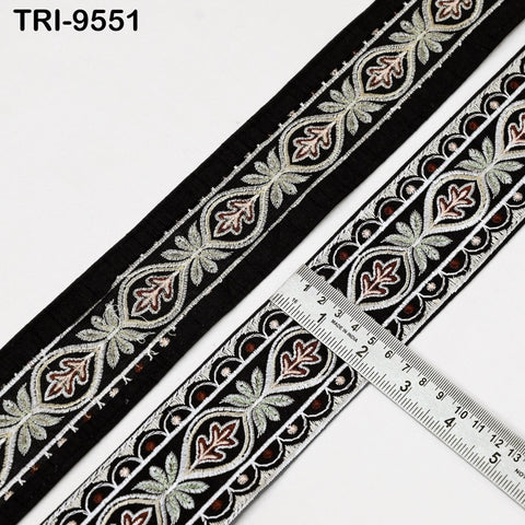 a decorative black and white fabric with a repeating pattern of floral and leaf designs. A ruler is placed next to the fabric, indicating the size or length of the fabric.