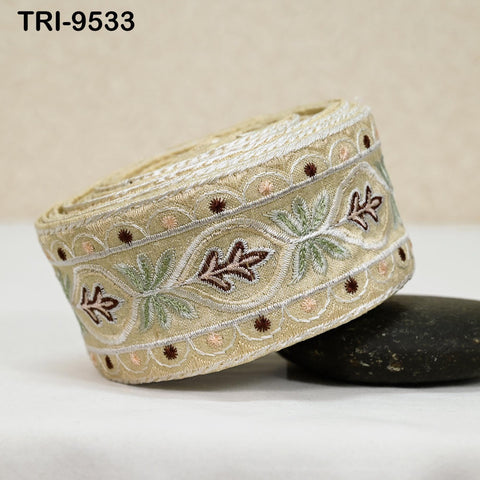A decorative beige fabric with a floral pattern, featuring a repeating design of leaves and flowers in shades of green and brown.