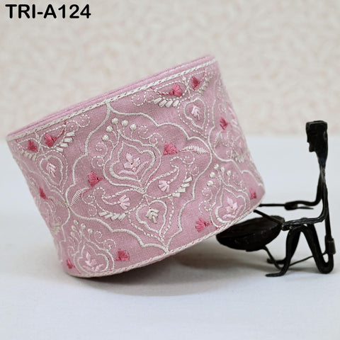a pink fabric with a floral pattern, and a small black metal figure or sculpture is placed next to it.