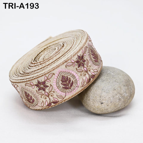 a decorative beige fabric with floral patterns, placed on a white surface next to a gray rock.