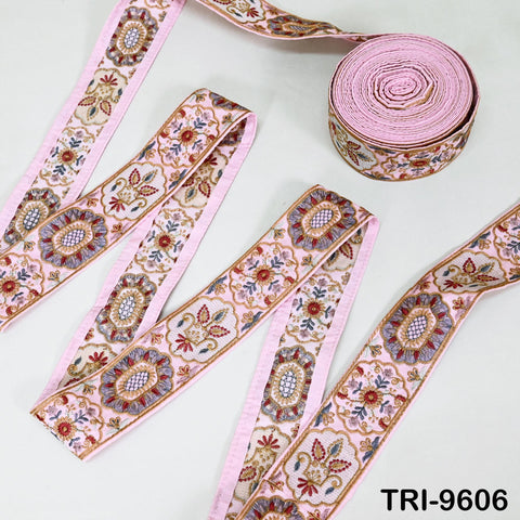 a collection of pink and white embroidered fabric pieces, including a large piece of fabric with a floral pattern and a smaller piece with a geometric pattern. The fabric appears to be part of a decorative textile or accessory.