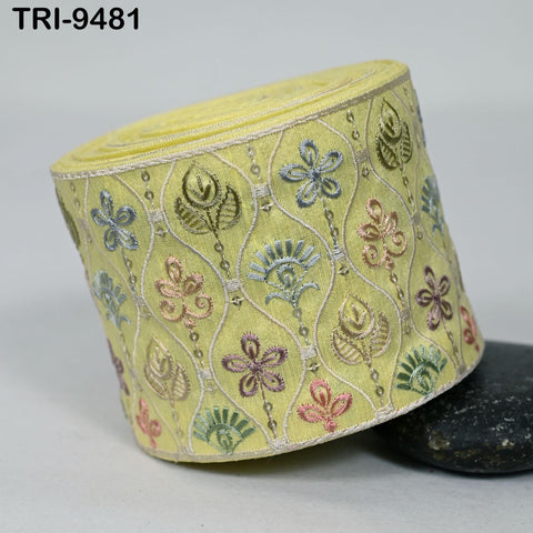 a decorative yellow fabric with a floral pattern, including various colored flowers and leaves.