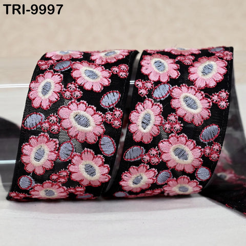 two rolls of ribbon with a floral pattern in shades of pink and black. The ribbon appears to be made of a shiny material and is displayed against a light background.