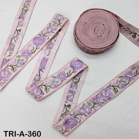 a pink floral embroidered ribbon and a spool of the same ribbon, both placed on a white surface.