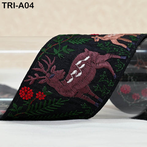 a decorative fabric with a deer embroidered on it, along with red flowers and green leaves. The fabric appears to be a ribbon or a piece of cloth.