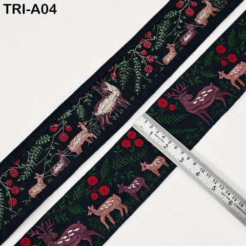 a decorative fabric with a repeating pattern of deer and flowers, including red flowers and green leaves. The fabric is displayed on a white background, and a ruler is placed next to it, indicating the size of the fabric.
