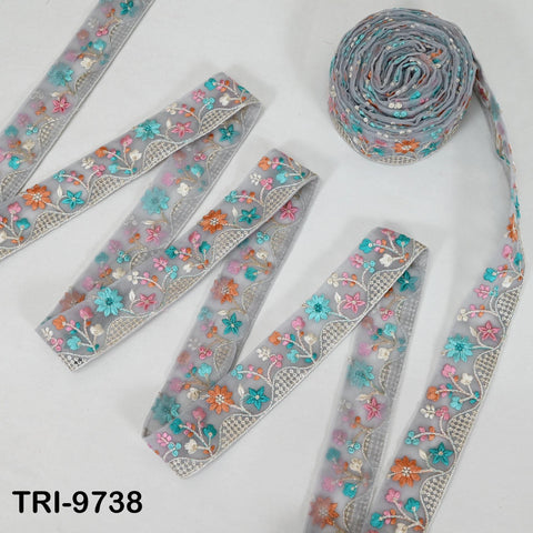 several spools of grey fabric with colorful floral embroidery, arranged on a white background.