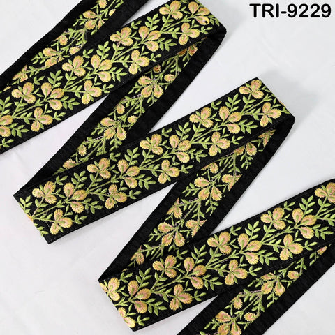 a close-up view of a decorative fabric with a floral pattern in black and gold colors. The fabric appears to be a ribbon or a piece of cloth with a similar design.