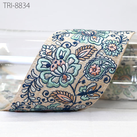 a decorative fabric with a floral pattern in shades of blue, green, and orange. The fabric appears to be a piece of cloth or textile, possibly used for a decorative purpose or as a textile product.