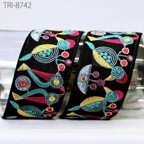 two black fabric pieces with colorful, abstract embroidered designs on them.
