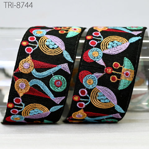 two pieces of black fabric with colorful, abstract embroidered designs on them.