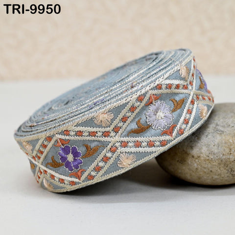 A decorative fabric with a floral pattern, featuring a combination of blue, purple, and orange colors, is displayed on a surface.